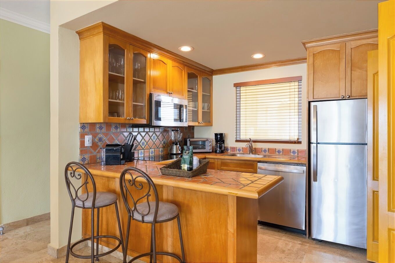 A kitchen with wooden cabinets, a stainless steel refrigerator, a microwave, and a coffee maker.