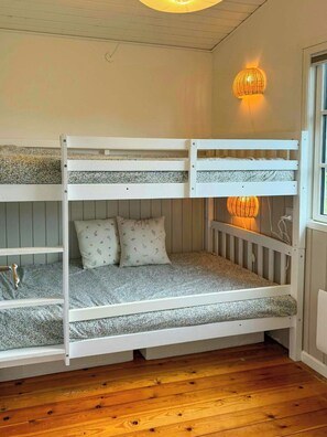 A bunk bed with a wooden floor and a window to the right. - Summer house on Fejø with field views and beach (Fejø)