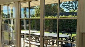 Ein Zimmer mit großen Glasfenstern und Zugang zu einer Terrasse mit Tisch und Stühlen.