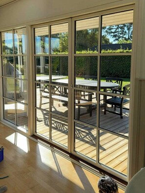 A room with large glass doors leading to an outdoor deck with a table and chairs. - Summer house on Fejø with field views and beach (Fejø)