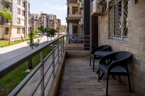 A balcony with outdoor seating, a view of a residential street, and a building with a stone facade. - CK 803 . Spacious 2BR Apt., 2 Baths (Sheikh Zayed City)