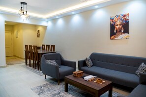 Ein modernes Wohnzimmer mit einer Couch, Sesseln, einem Couchtisch und einem Essbereich mit Stühlen und Tisch.