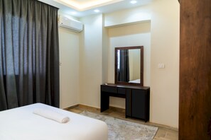 A hotel room with a bed, a desk, a mirror, and an air conditioning unit. - CK 803 . Spacious 2BR Apt., 2 Baths (Sheikh Zayed City)