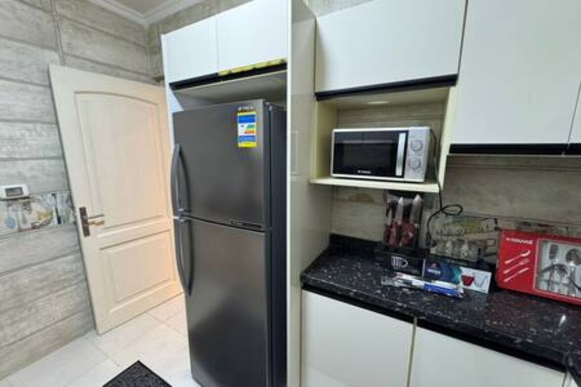 A compact kitchen with a refrigerator, microwave, and a small countertop.