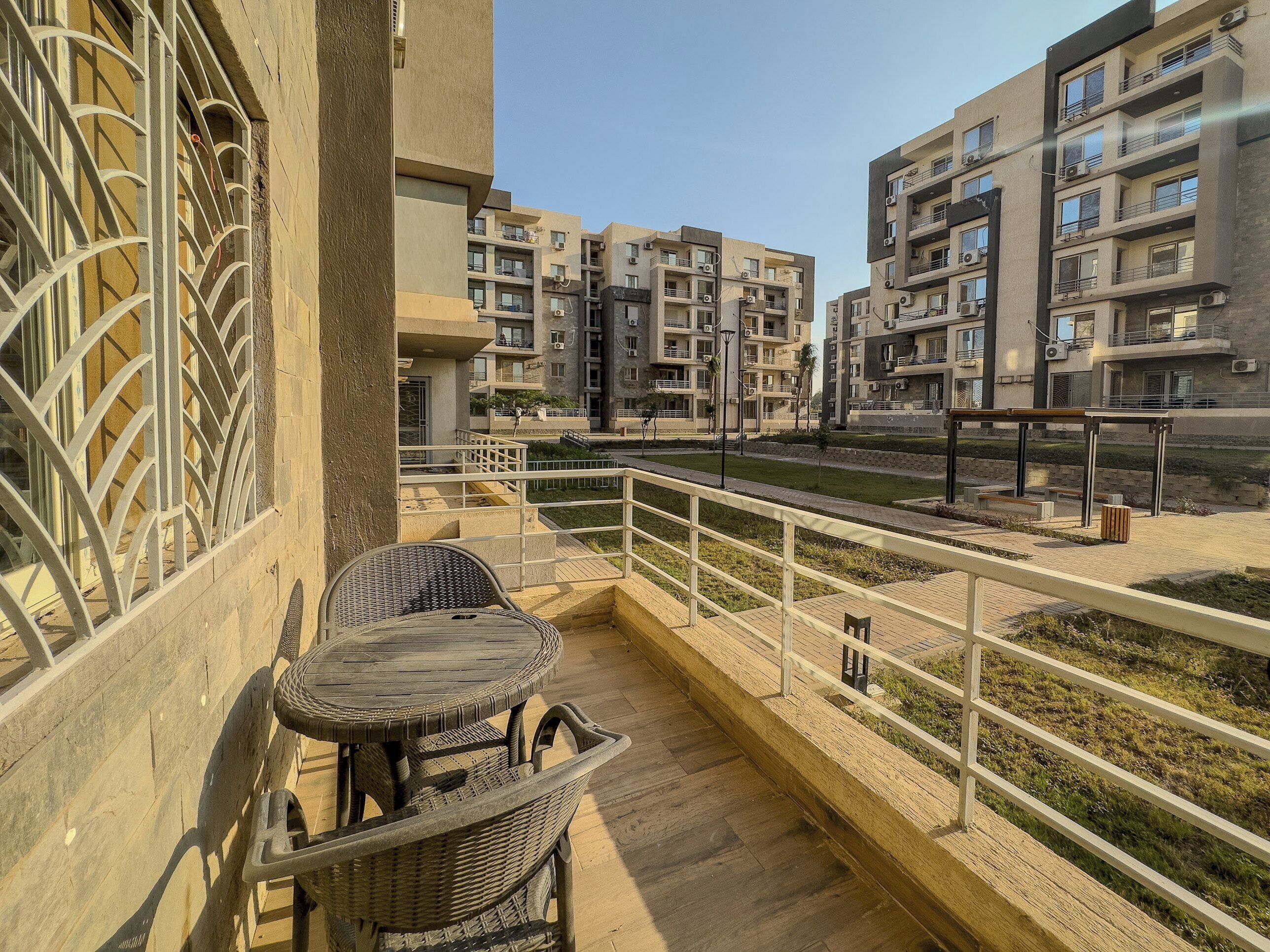 Un balcon doté de meubles en osier et offrant une vue sur des immeubles d’habitation.
