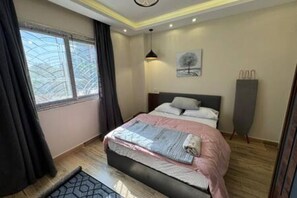 A bedroom with a bed, a window, a painting, and a radiator. - CK 903 . Spacious 2BR Apt., 2 Baths (Sheikh Zayed City)