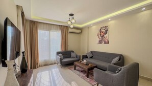A modern living room with a sofa, armchairs, a coffee table, and a TV. - CK 903 . Spacious 2BR Apt., 2 Baths (Sheikh Zayed City)