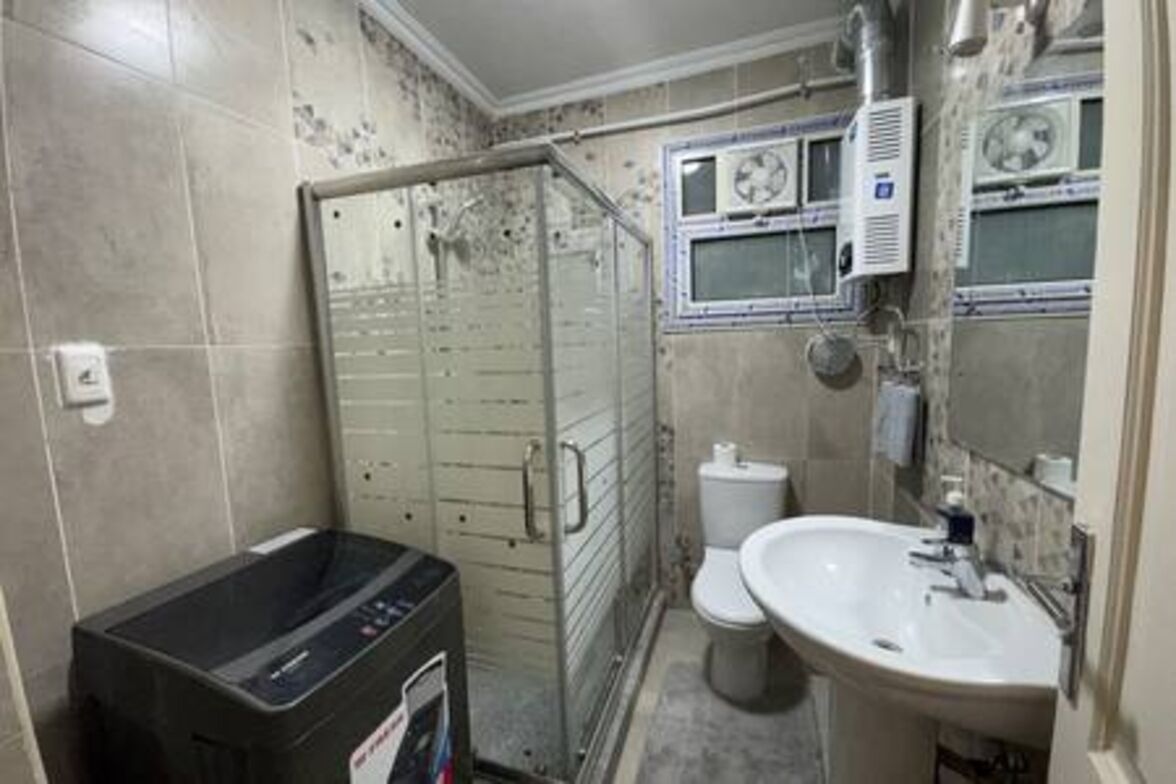 A small, compact bathroom with a shower enclosure, a toilet, and a sink.