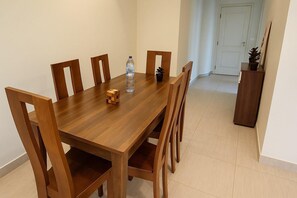 Een houten eettafel met stoelen, een waterfles, een drinkbeker en een Rubik's Cube.