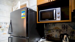 Et køkken med et sort køleskab og en mikrobølgeovn oven på et træskab.