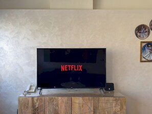 A television on a wooden stand with a remote control beside it. - 1406.  Elegant 2BR Apt | Sun Terrace | Ensuite (Almazah)