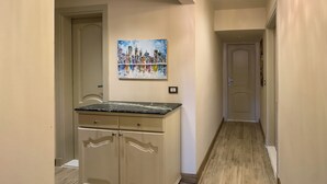 A hallway with a kitchen counter, cabinets, and a painting on the wall. - 1406.  Elegant 2BR Apt | Sun Terrace | Ensuite (Almazah)