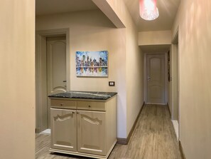 A hallway with a kitchen counter, cabinets, and a painting on the wall. - 1406.  Elegant 2BR Apt | Sun Terrace | Ensuite (Almazah)