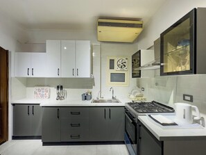 A modern kitchen with white cabinets, a stove, a sink, and an air conditioning unit. - 1406.  Elegant 2BR Apt | Sun Terrace | Ensuite (Almazah)