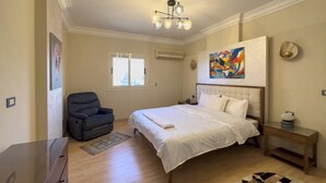 A hotel room with a bed, a chair, a desk, a rug, and a painting on the wall. - 1406.  Elegant 2BR Apt | Sun Terrace | Ensuite (Almazah)