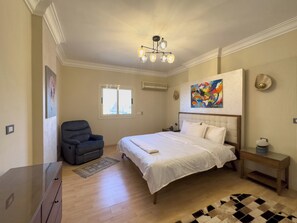 A hotel room with a bed, a chair, a desk, a rug, and a painting on the wall. - 1406.  Elegant 2BR Apt | Sun Terrace | Ensuite (Almazah)