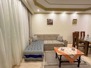 Ein Zimmer mit einer Couch, einem Esstisch und einem gemusterten Teppich.