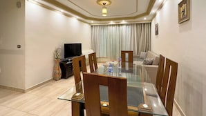 Un comedor moderno con una mesa de vidrio, sillas de madera, un televisor y un sofá.