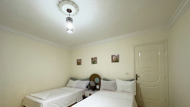 Habitación de hotel con dos camas, una puerta y una lámpara en el techo.
