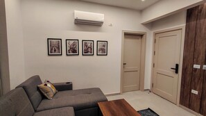 A living room with a sofa, a coffee table, and four framed pictures on the wall. - 832 . Modern 1BR Apartment | Near AUC (New Cairo City)