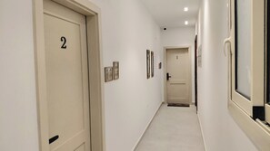 Ein Flur mit den Nummern 1 und 2 auf den Türen, einem hellen Boden und gerahmten Bildern an den Wänden.