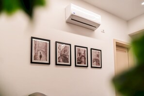 Un muro con quattro fotografie in bianco e nero incorniciate raffiguranti un canale, un condizionatore d'aria sopra e una porta a destra.