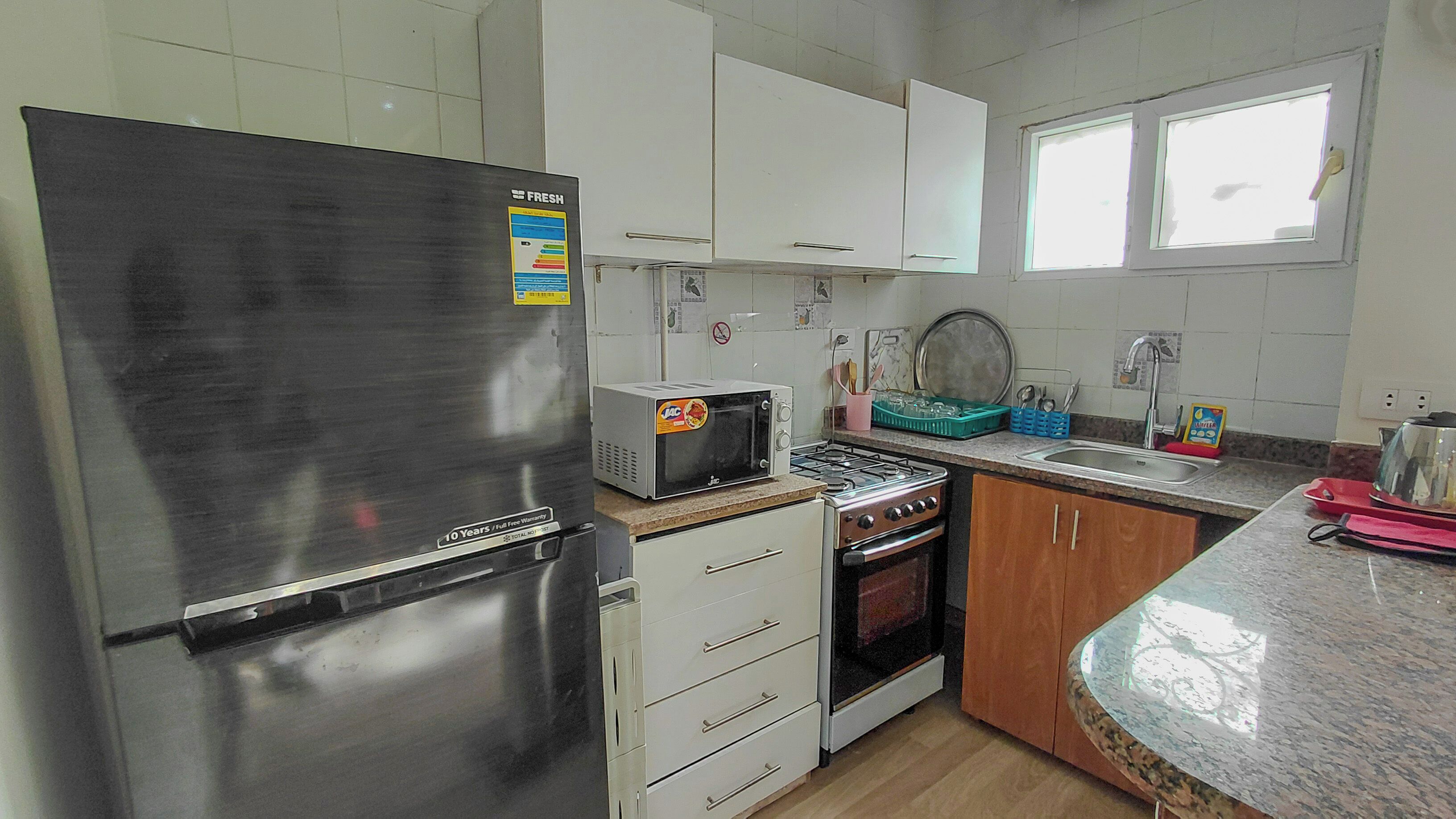 A kitchen with a stainless steel refrigerator, a microwave, a stove, and wooden cabinets.