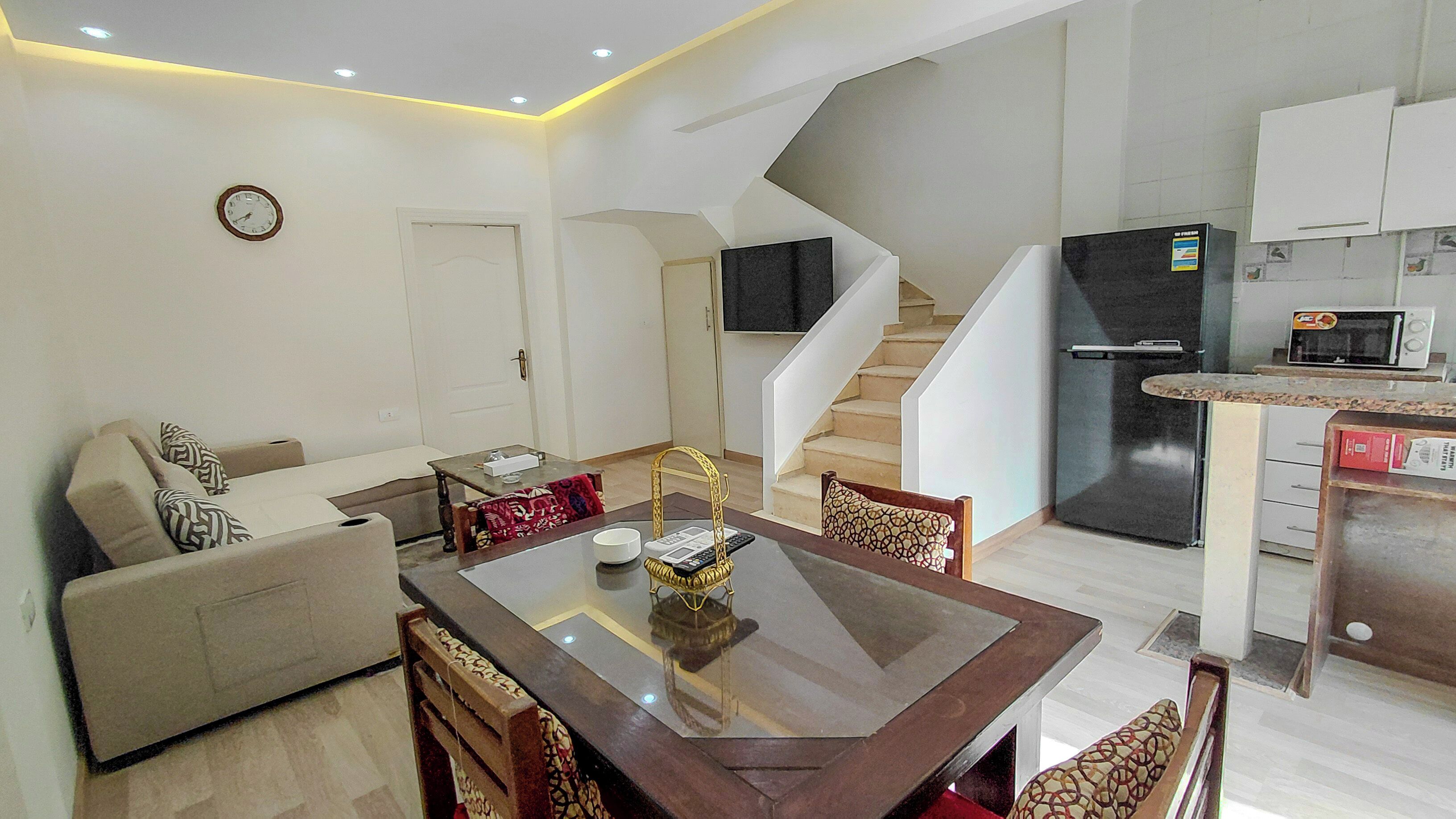 Un apartament modern amb zona de menjador, sala d'estar, cuina i una escala.