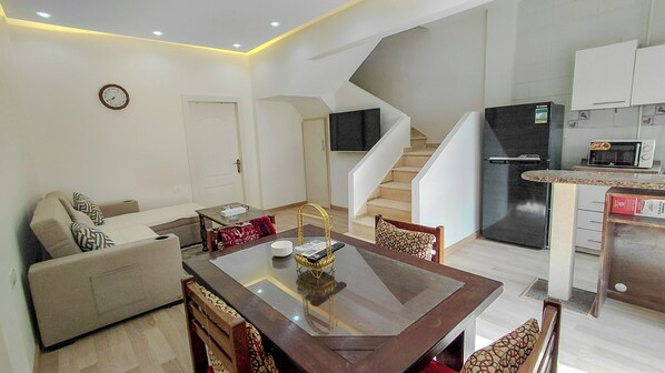 A modern apartment with a dining area, living room, kitchen, and a staircase.
