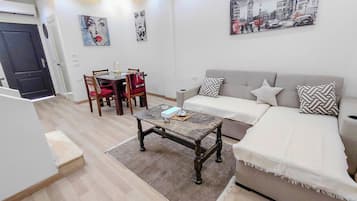 Un salon comprenant un canapé, une table basse, une table à manger avec des chaises et des œuvres d’art accrochées aux murs.