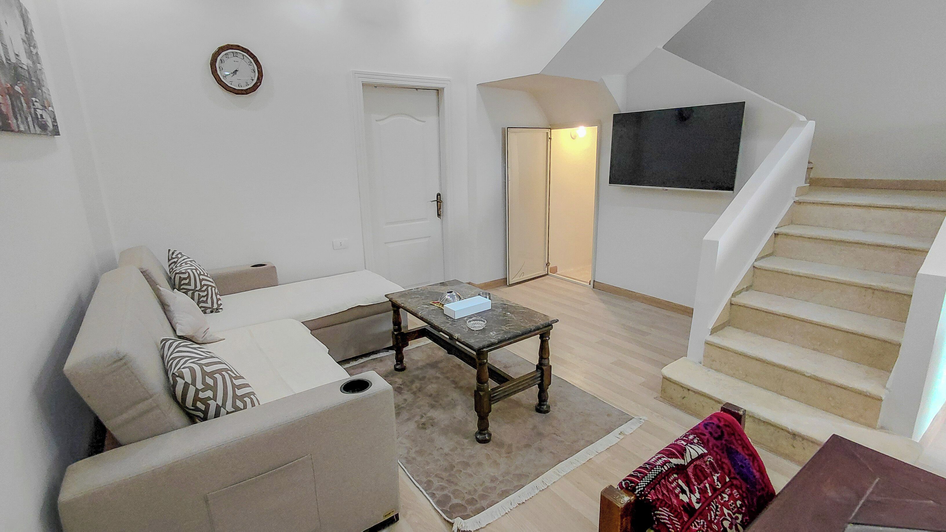 A living room with a sofa, a coffee table, and a staircase leading to an upper level.