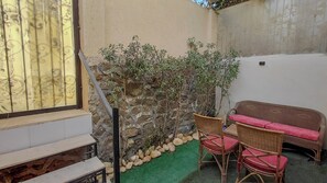 A small outdoor seating area with wicker furniture and a stone wall.