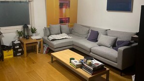 Un salon avec un canapé gris, une table basse en bois et un tableau accroché au mur.