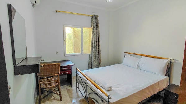 A bedroom with a single bed, a desk, and a chair.