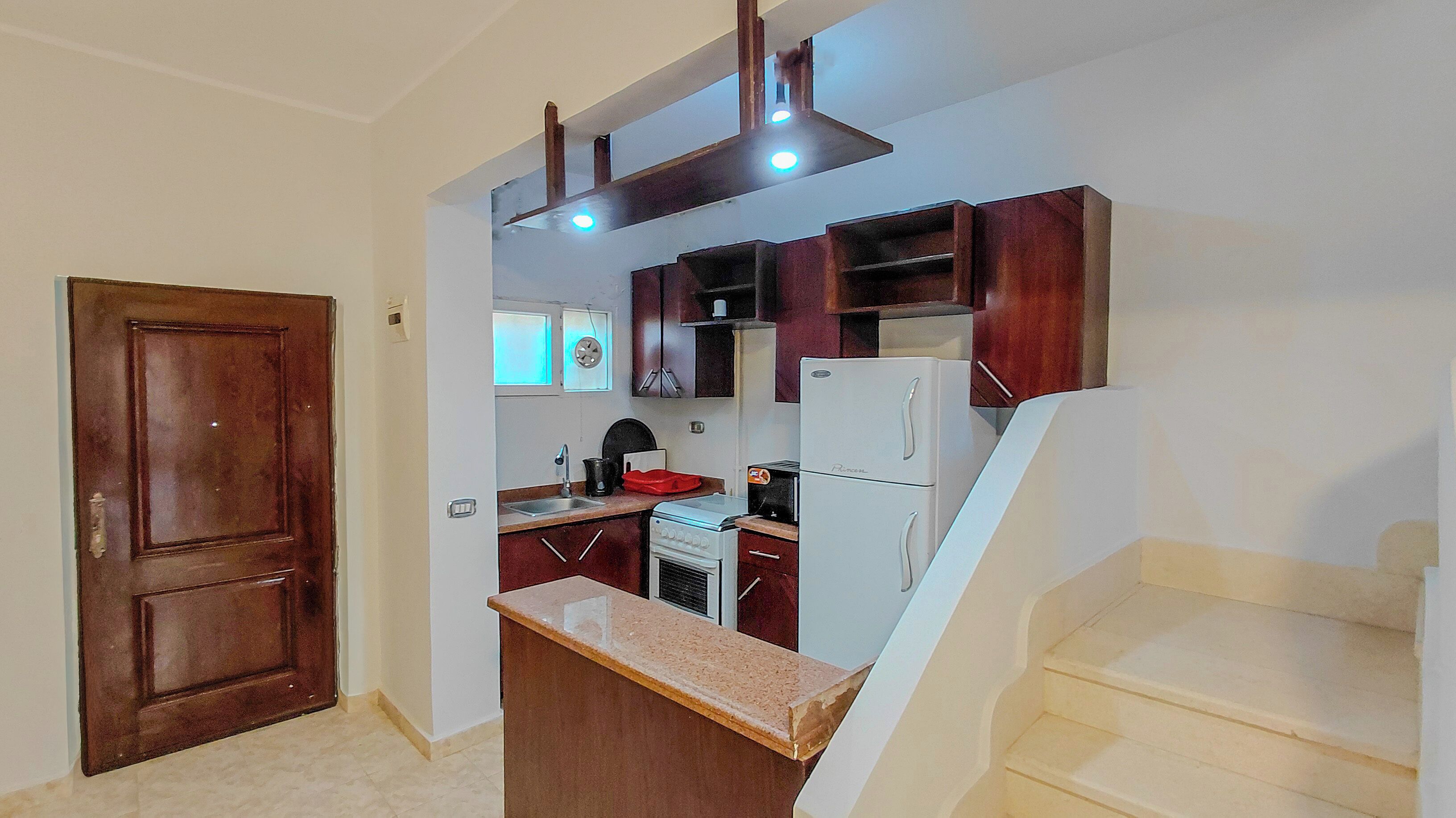 A kitchen with a built-in stove, a refrigerator, and wooden cabinets.