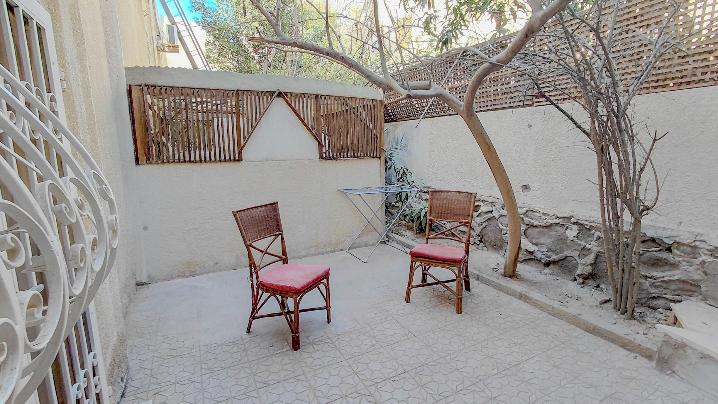 A small outdoor seating area with two wicker chairs and a metal table.