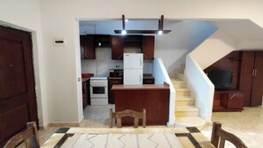 A compact kitchen with a built-in oven, a white refrigerator, and a microwave.