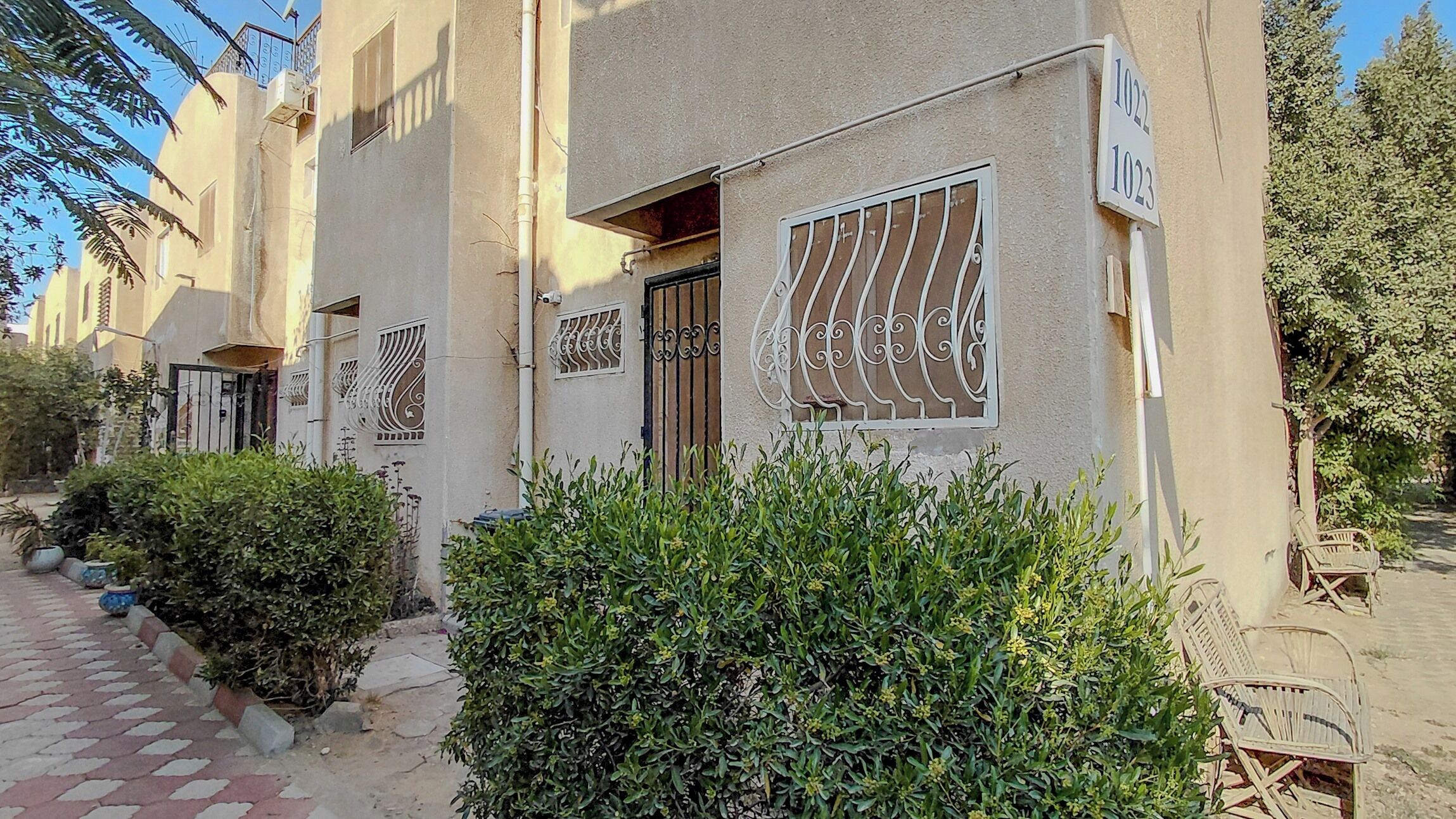 A residential building with numbered windows, a gated entrance, and a paved pathway.