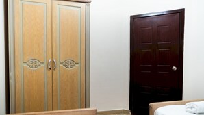 Un dormitorio con un armario de madera, una puerta oscura y una cama con cubrecama blanca.