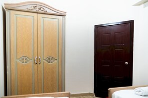 Una camera da letto con un armadio in legno, una porta scura e un letto con copripiumino bianco.