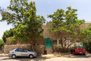 Un edificio con una porta verde, un muro di pietra e due auto parcheggiate.