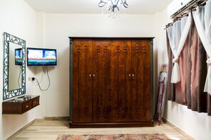 A room with a wooden wardrobe, a television, a mirror, and a chandelier. - 575 · 4BR Townhouse, 3 Bath, TV, Backyard (Sheikh Zayed City)