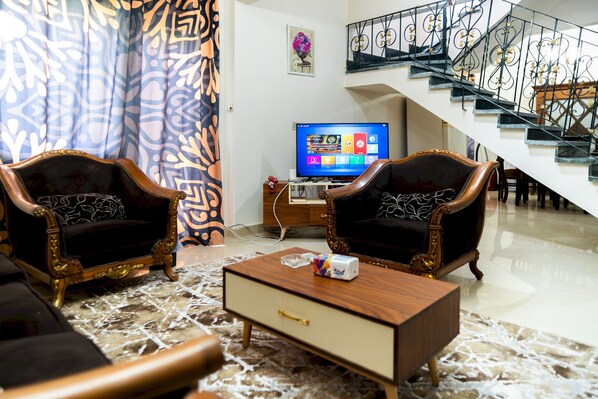 Una sala de estar con dos sillones, una mesa de centro, un televisor y una escalera.
