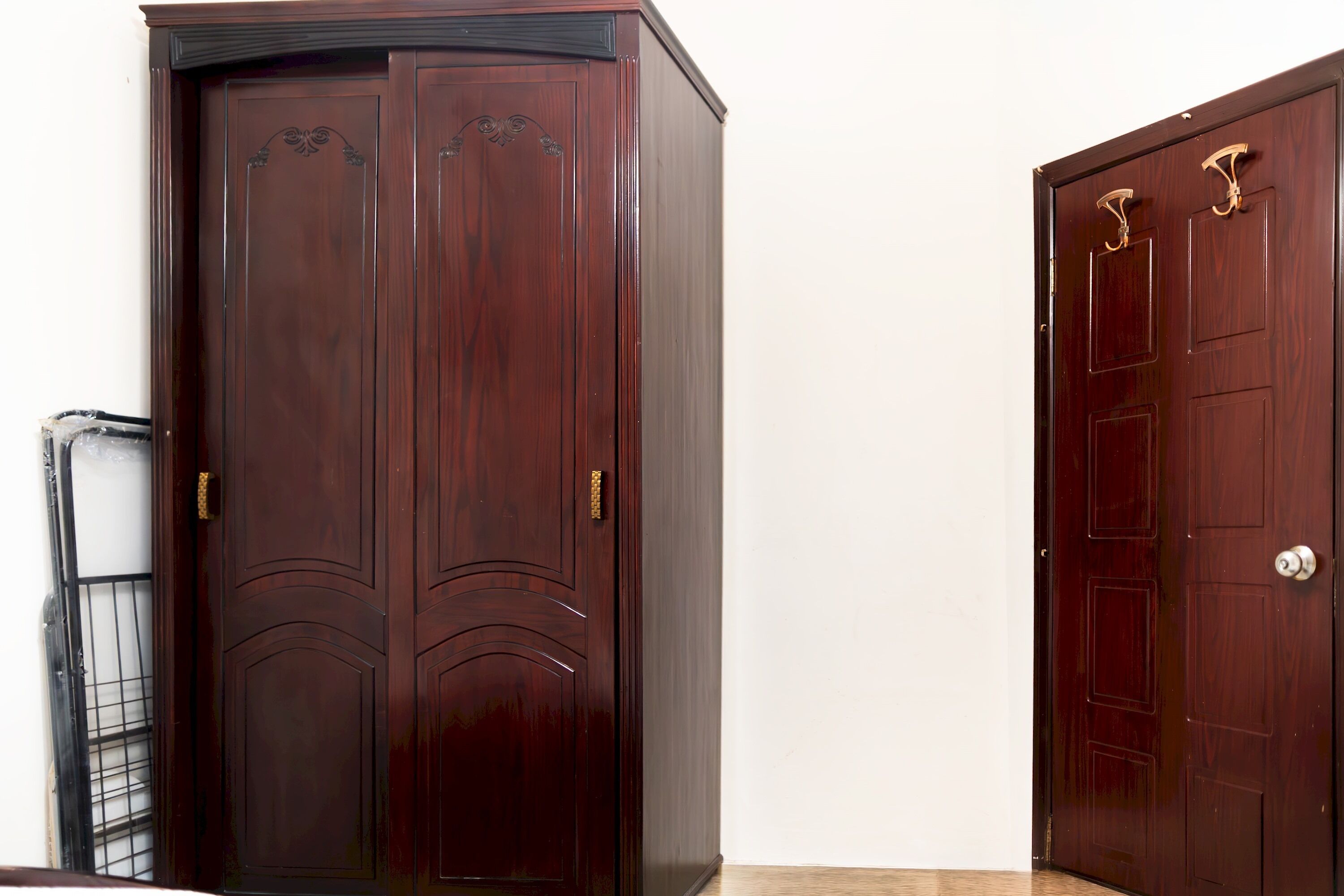 A closed wooden wardrobe with a handle and a door with a lock.