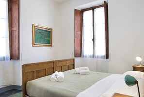 A room with a bed, a painting, and a window with curtains. - Chiarello 4 – Ampia Casa nel Borgo Antico (Taceno)