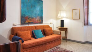 A room with a sofa, a lamp, and a painting on the wall.