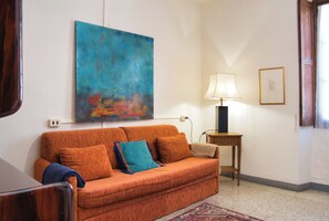 A room with a sofa, a lamp, and a painting on the wall.