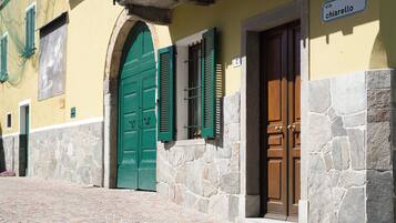 A building with a green door and a brown door, stone walls, and a cobblestone street.