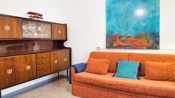 A room with a wooden cabinet, a sofa, and a large abstract painting.