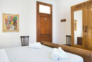 Ein Hotelzimmer mit einem Bett, einer Holztür, einem großen Spiegel und einem Bild an der Wand.